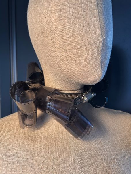 A sculptural neckpiece made of various glass and transparent elements on a mannequin.